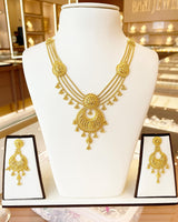 Elegant bird-inspired pendant set displayed, featuring a necklace and matching earrings in intricate gold design.